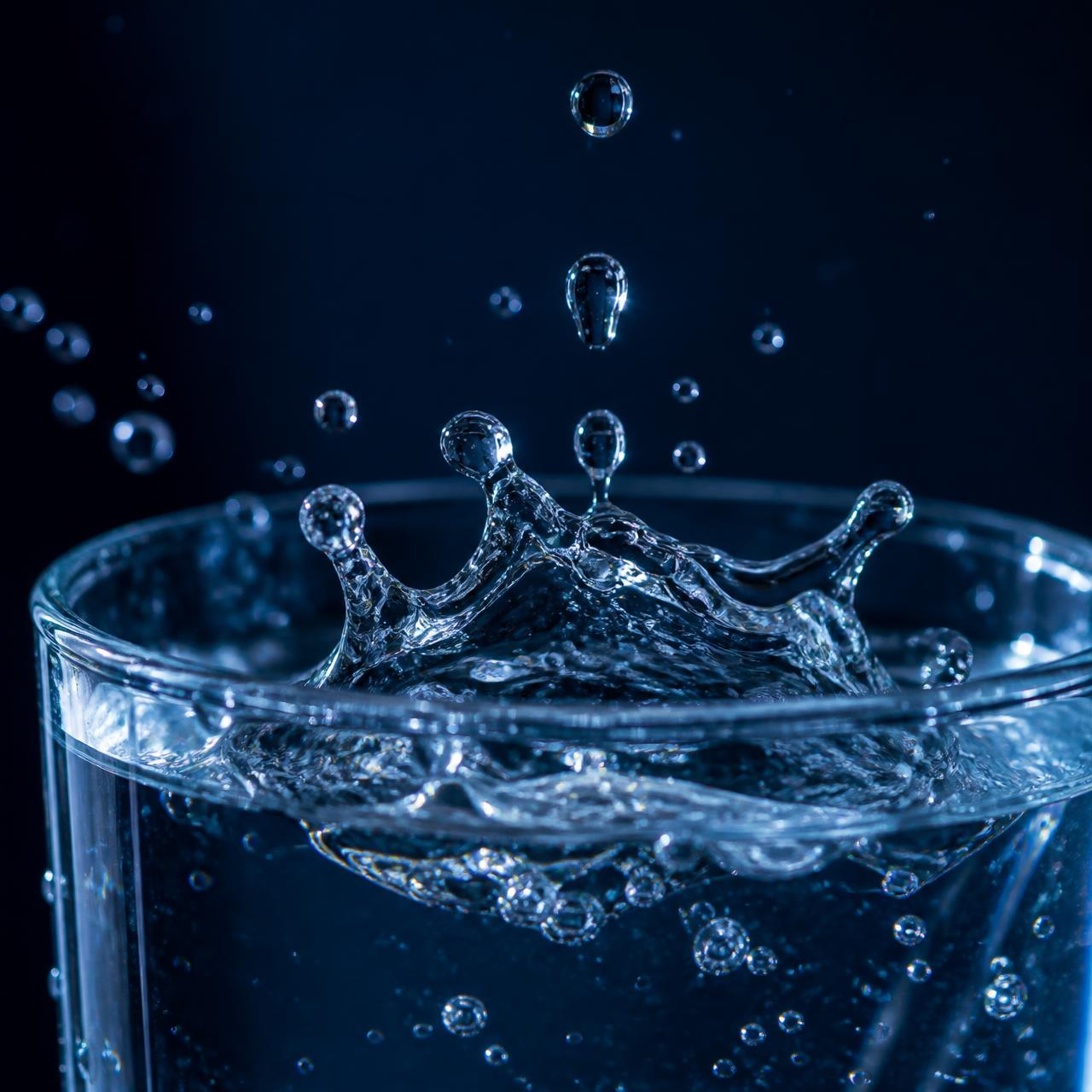 Clean drinking water droplets falling into a glass